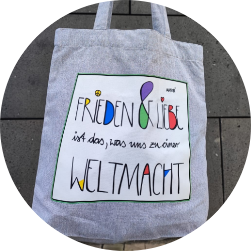 grauer Stoffbeutel mit bunter Schrift "Frieden & Liebe ist das, was uns zu einer Weltmacht"